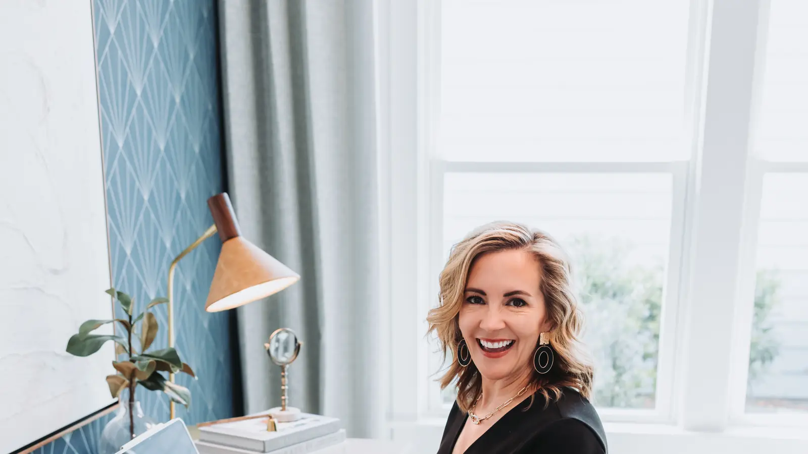 Lucy Thornton at her desk with a laptop, laughing toward the camera